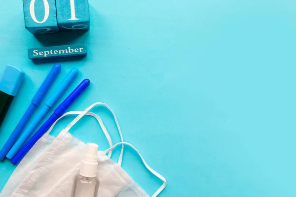 School supplies and medical mask on blue background. Copy space for the text. School quarantine concept