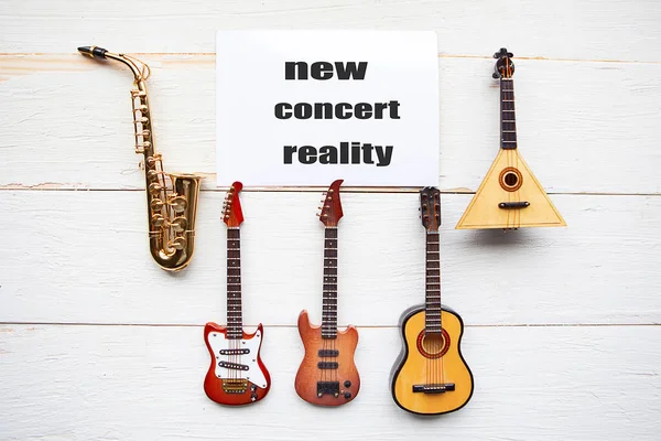 Musical instruments and card with message New Concert Reality on wooden background.  Concert quarantine concept