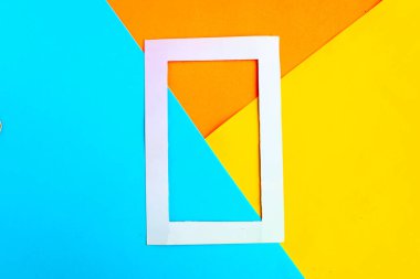 Parlak geometrik turuncu, sarı ve mavi arkaplanlı beyaz fotoğraf çerçevesi. Minimum konsept. Metin için alanı kopyala