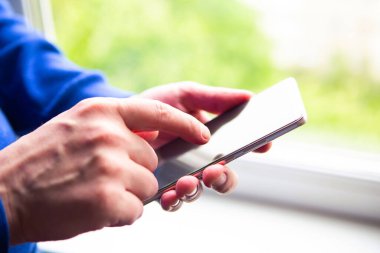 Pencerenin yanında cep telefonu kullanan bir adama yaklaş