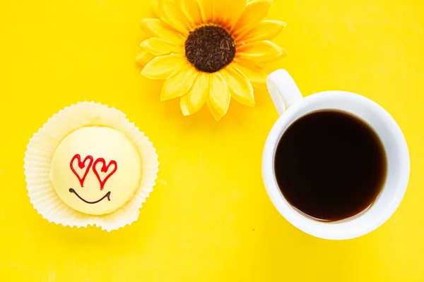 Tasty sweet cake with draw face and heart eyes on yellow background, top view. Love concept.