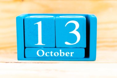 13 Ekim. Ahşap zemin üzerinde ay ve tarih olan mavi küp takvimi.