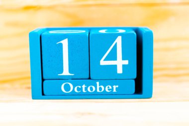 14 Ekim. Ahşap zemin üzerinde ay ve tarih olan mavi küp takvimi.