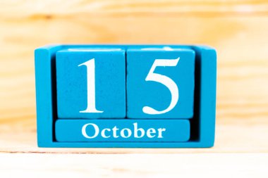 15 Ekim. Ahşap zemin üzerinde ay ve tarih olan mavi küp takvimi.