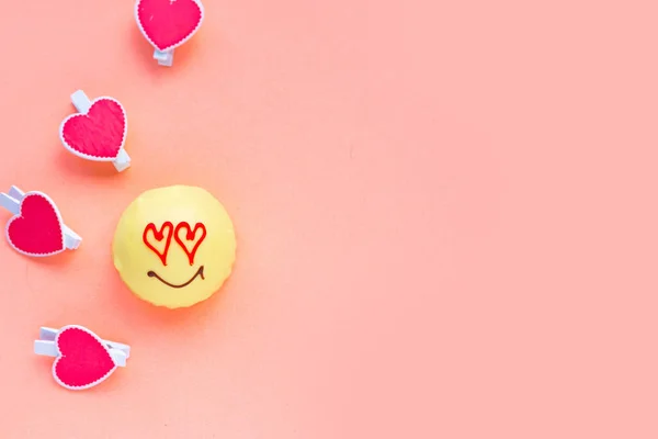 Tasty sweet cake with draw face and heart eyes on pink background, top view. Love concept. Copy space, banner