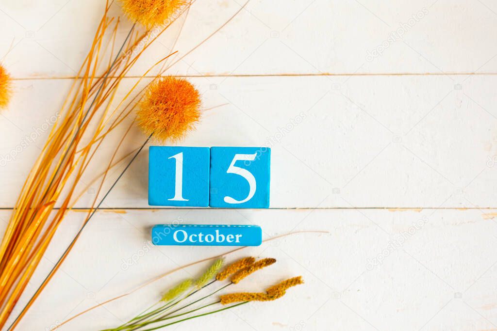 October the 15th. Blue cube calendar with month and date on wooden background. Copy space for the text