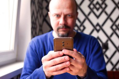 Cep telefonunu kullanan ve ona bakan adam.