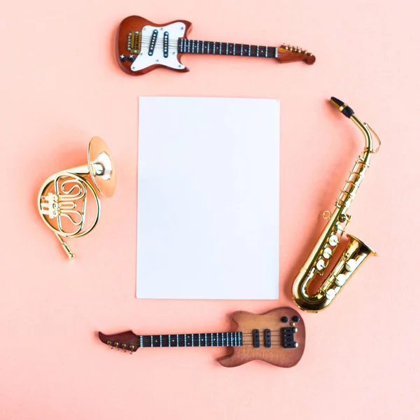 Toy music instruments and white mockup blank on pink background, top view, copy space for the text