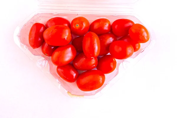 Cherry tomatoes in the box, top view, pink background