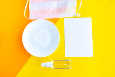 Antiseptik, tıbbi maske ve arka planda boş bir tabak. Minimum konsept. Covid-19 konsepti