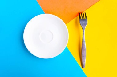 Renkli geometrik arka planda beyaz model plaka ve çatal. Metin için alanı kopyala. Asgari konsept