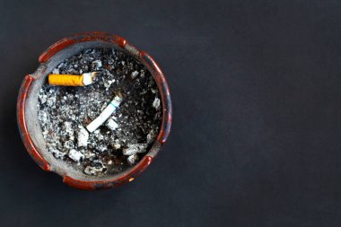 Siyah arkaplanda sigara izmaritleri olan kül tablası, üst görünüm, metin için kopyalama alanı