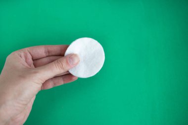 Yeşil arkaplanda pamuklu sünger tutan kadın, metin için kopyalama alanı, asgari konsept