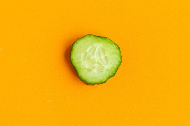  Dilimlenmiş taze salatalık turuncu arka planda izole edilmiş, üst manzara, minimum konsept