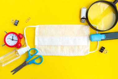 Okul malzemeleri ve tıbbi maske, parlak sarı arka plan, üst manzara. Okul konseptine, okul karantinasına