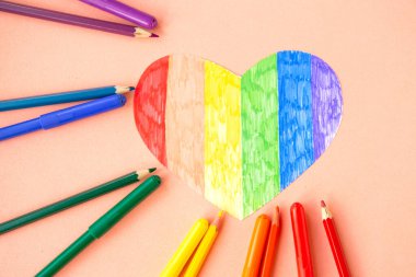 Lgbtq renklerinde kalp ve pastel pembe arka planda kalemler, üst görünüm
