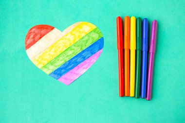 Nane yeşili arka planda lgbtq renklerinde kalp ve kalemler, üst görünüm