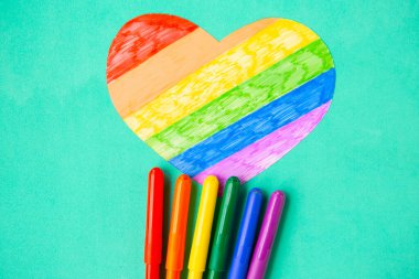 Nane yeşili arka planda lgbtq renklerinde kalp ve kalemler, üst görünüm