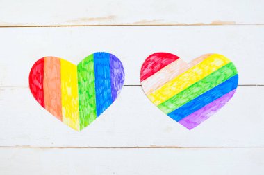 Ahşap arka planda lgbtq renginde iki kalp, üst görünüm