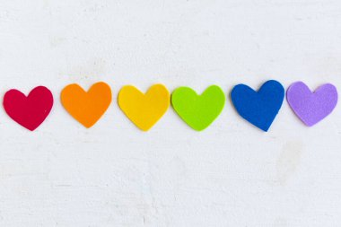 Beyaz ahşap arka planda lgbtq renginde kalpler, üst görünüm