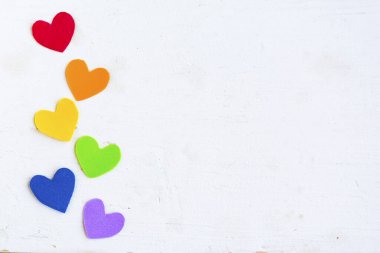 Beyaz ahşap arkaplanda lgbtq renginde kalpler, üst görünüm, boşluk kopyala