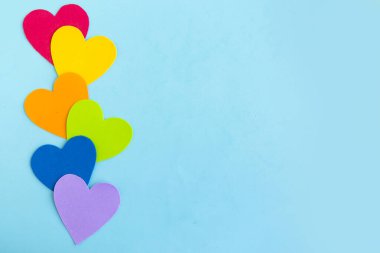 Mavi arkaplan üzerindeki lgbtq renklerindeki kalpler, üst görünüm, boşluk kopyala