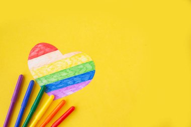 lgbtq renklerindeki kalp ve parlak sarı arkaplan üzerindeki kalemler, üst görünüm, boşluk kopyala