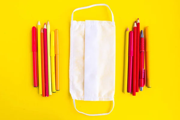 색연필 과노란 배경의 의료용 마스크 학교의 개념으로 돌아가 봅시다 — 스톡 사진