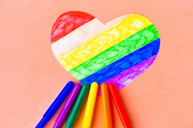 Pembe arka planda lgbtq renklerinde kalp ve renkli kalemler, üst görünüm