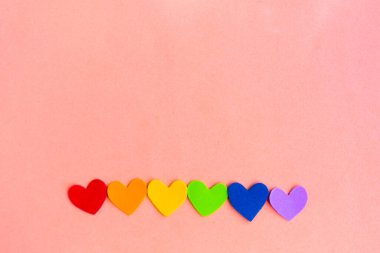 Pastel pembe arkaplan üzerinde lgbtq renginde kalpler, üst görünüm, boşluk kopyala