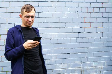Duvarında cep telefonu olan modern bir gencin sokak portresi.