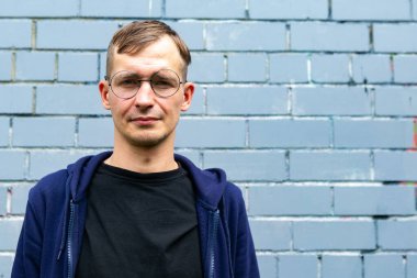 Gri tuğla duvara karşı genç ve yakışıklı bir adamın portresi. Bir sürü boşlukName.