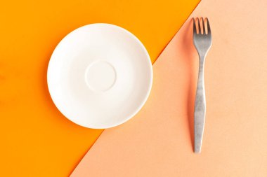 Turuncu geometrik arka planda beyaz model plaka ve çatal. Metin için alanı kopyala. Asgari konsept