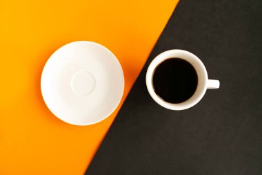 Geometrik turuncu ve siyah arkaplanlı beyaz tabak ve kahve fincanı. Asgari konsept