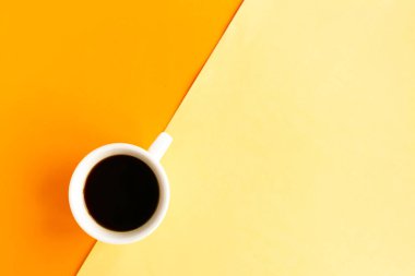 Geometrik turuncu ve sarı arkaplan üzerine kahve fincanı, üst görünüm, metin için kopya alanı, asgari konsept