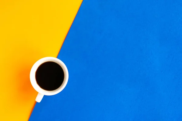 Coffee cup on geometric orange and blue background, top view, copy space for the text, minimal concept