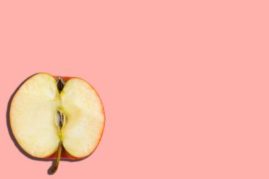 Pastel pembe arka planda dilimlenmiş kırmızı elma, minimal konsept, kopyalama alanı, afiş