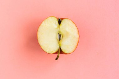 Pastel pembe arka planda dilimlenmiş kırmızı elma, minimum konsept