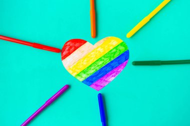 Yeşil arkaplanda lgbtq sütunlarında kalp ve renkli kalemler, üst görünüm