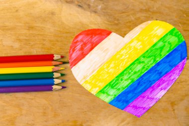Lgbtq renklerinde kalemler ve tahta arka planda kalp, üst görünüm