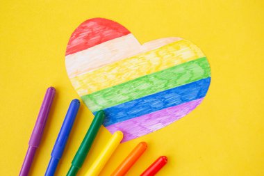 lgbtq renklerinde kalp ve parlak sarı arka planda kalemler, üst görünüm