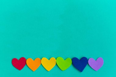 Turkuaz arkaplan üzerindeki lgbtq renklerindeki kalpler, üst görünüm, boşluk kopyala