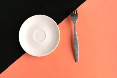 Pembe ve siyah arka planda boş tabak ve çatal. Metin için alanı kopyala. Asgari konsept