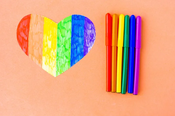 Lgbtq renklerinde kalp ve pastel pembe arka planda kalemler, üst görünüm