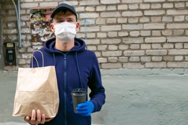 Koruyucu maskeli kurye paket yemek getiriyor. Coronavirus covid-19 salgını.