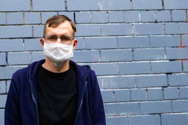 Tuğla arka planda koruyucu maskeli bir adamın portresi. Mikropları önlemek için maskeli bir gencin yüzü..