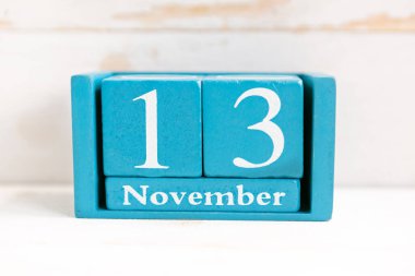 13 Kasım. Ahşap zemin üzerinde ay ve tarih olan mavi küp takvimi.