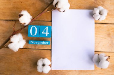4 Kasım. Ahşap zemin üzerinde ay ve tarih olan mavi küp takvimi.