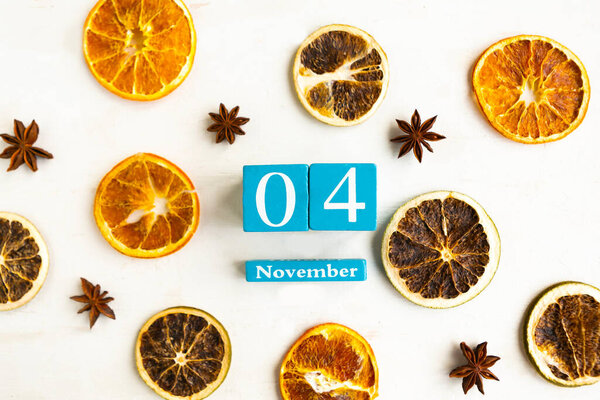 4 ноября. Голубой кубический календарь с месяцем и датой на деревянном фоне.