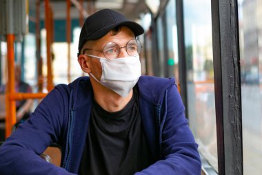 Otobüste koruyucu maskeli bir adam var. Coronavirus covid-19 salgını sırasında toplu taşıma